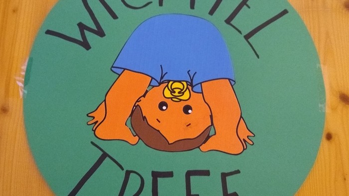 Ein Cartoon-Mädchen mit orangefarbenen Haaren und blauer Bluse, das auf dem Kopf steht, ist auf einem grünen Kreis mit dem Text 