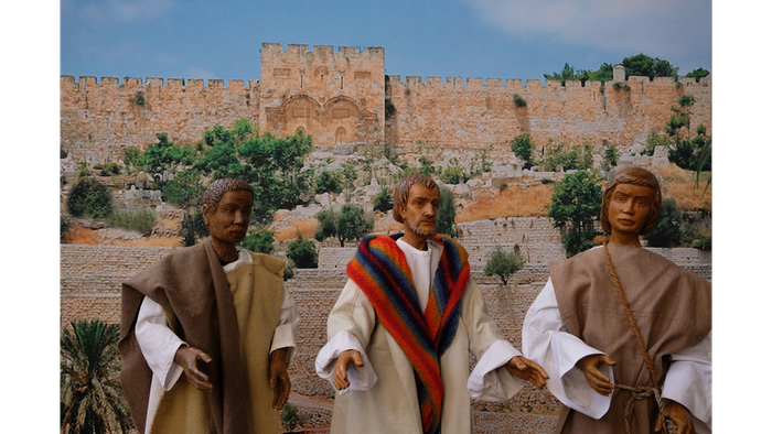 Drei Männer in traditioneller Kleidung vor alter Burgmauer