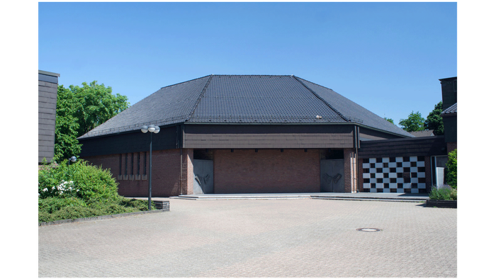 Modernes Gebäude mit geschlossenen Garagentoren, schwarz-weiß karierter Wandpaneele und klarem Himmel im Hintergrund.