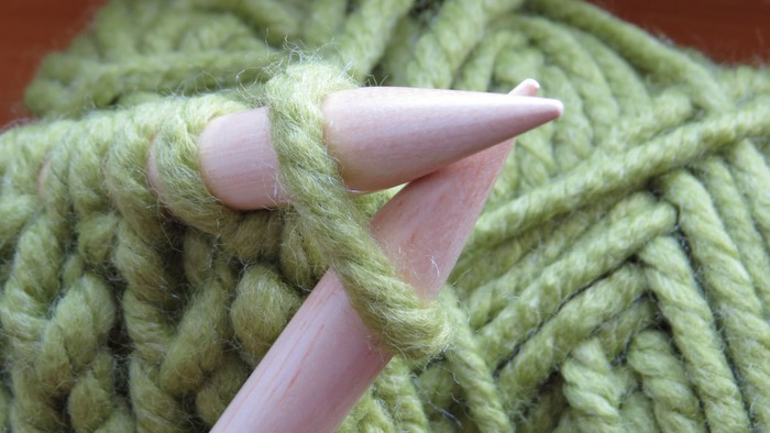 Knitting needles with green yarn.