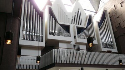 Ein großes, mehrstöckiges Pfeifenorgel mit schlankem, modernem Design und beleuchteter Beleuchtung in einem Konzertsaal.