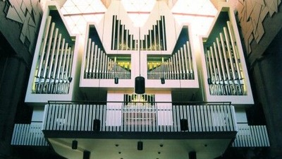 Eine große Pfeifenorgel mit mehreren Pfeifenreihen und komplexen Tastatursteuerungen in einem geräumigen Saal.