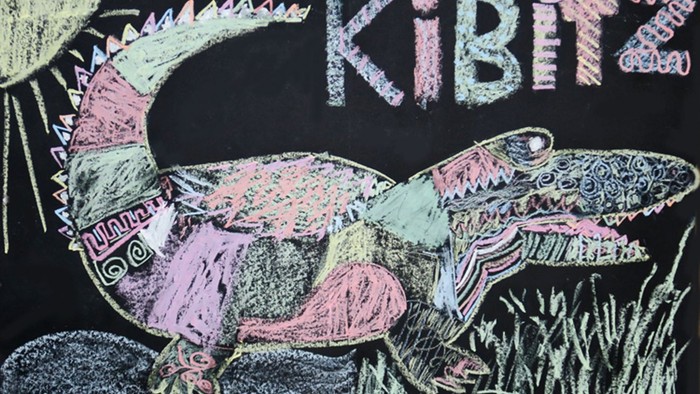 Ein buntes Krokodil liegt auf einem Felsen, darüber steht 