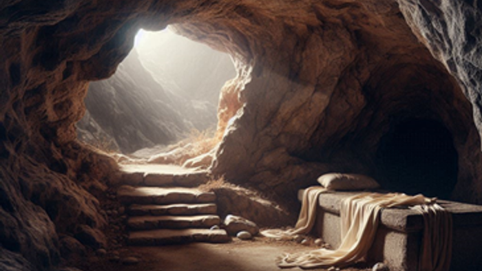 Gammel grotteindgang, der afslører et stentomb med ligklæder og oplyst af naturligt lys.