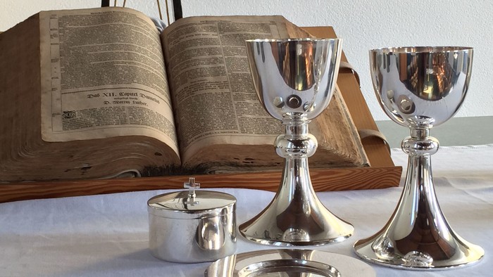 Silberne Kelche und Schale vor aufgeschlagenem Buch