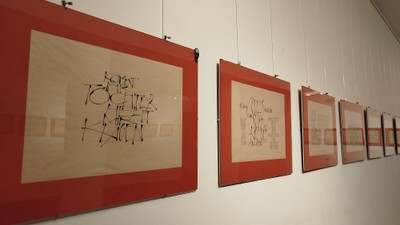 Abstrakte Kunstwerke mit roten Rahmen, die an einer minimalistischen Galeriewand ausgestellt sind.