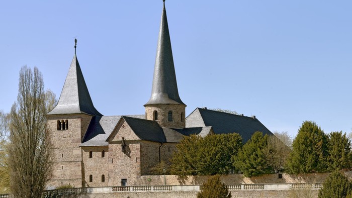 Historische Steinburg mit Zwillingstürmen und befestigten Mauern in einem gestalteten Innenhof.