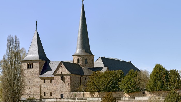 Historische Steinburg mit Zwillingstürmen und befestigten Mauern in einem gestalteten Innenhof.