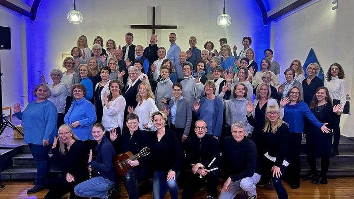 Eine große Gruppe, die fröhlich in einer Kirche posiert, wahrscheinlich nach einem Chor- oder Gemeindeevent.
