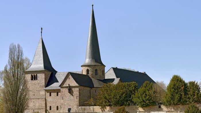 Historische Steinburg mit Zwillingstürmen und befestigten Mauern in einem gestalteten Innenhof.