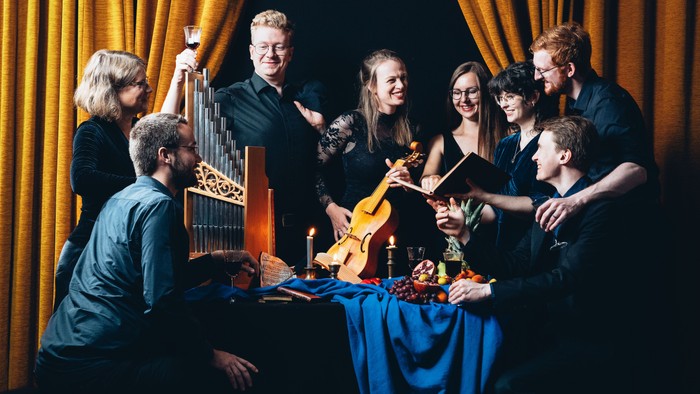 Eine Gruppe von Musikern posiert mit ihren Instrumenten vor einem Vorhang.