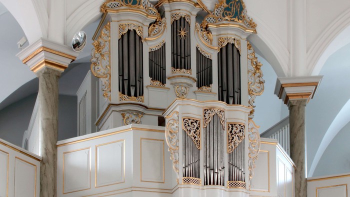 Elegant barokorgel i barokstil med forgyldte detaljer og indviklede udskæringer i en stor kirke.