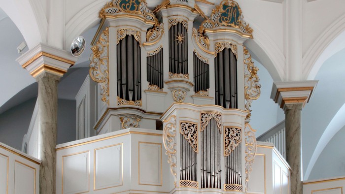 Elegant barokorgel i barokstil med forgyldte detaljer og indviklede udskæringer i en stor kirke.