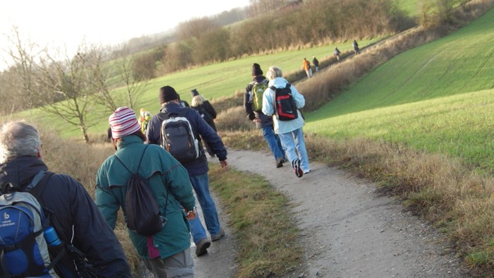 En gruppe af turister går på en sti gennem en grøn dal.