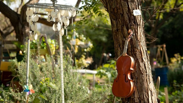 Geige hängt inmitten eines Gartens am Baum