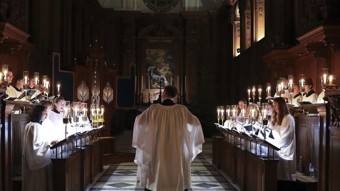 Chormitglieder in Messgewänder in von Kerzen erleuchteter Kirche.