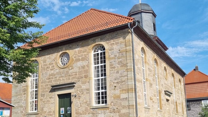 Altes Steinhaus mit grünen Tür und Uhr, rote Ziegeldächer, sonniger Tag