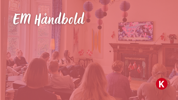 Se gruppe, der ser EM i håndbold med festlige dekorationer og hyggelig indendørs stemning.