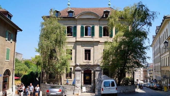 En stor, gammel bygning med grønne vinduer og en hvid van.