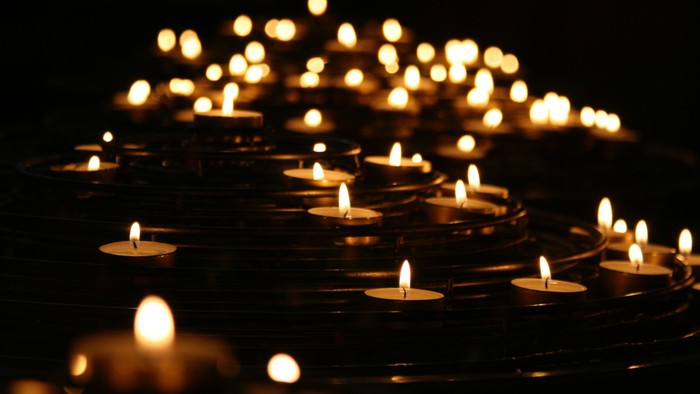 Numerous lit candles arranged in rows, creating a warm and serene atmosphere.