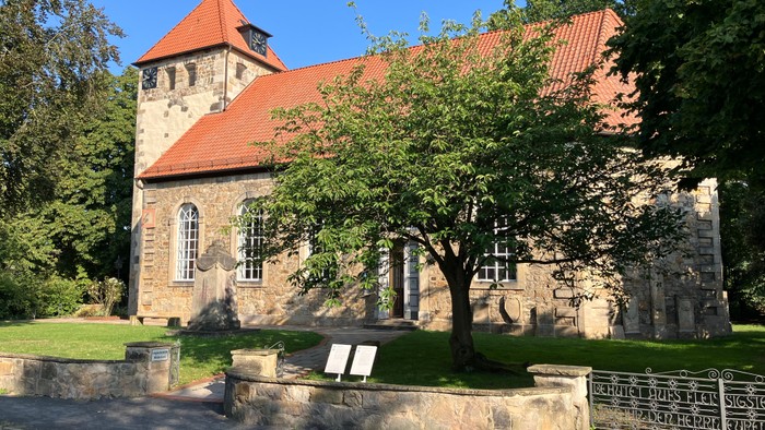 Alte Kirche mit rotem Dach und grünem Baum davor