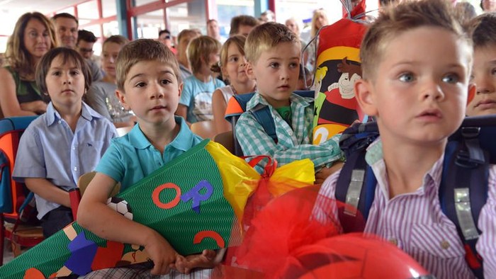 Kinder sitzen in einem Raum und halten bunte Geschenke.