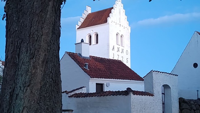Hvid kirke med rødt tag og klokketårn.
