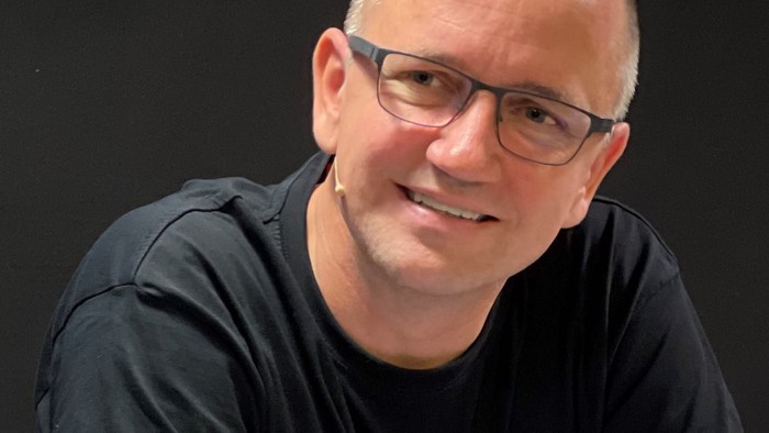 En smilende mand med briller og kort hår.