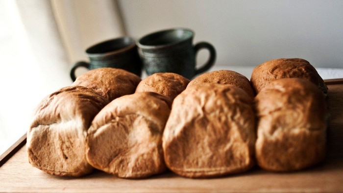 En række friskbagtede brød og to tæpper på et bord