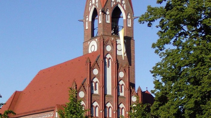 Die Kirche hat einen hohen Turm mit spitzem Dach und Zifferblatt.