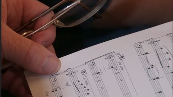 Eine Hand hält eine Lupe über einem technischen Diagramm.