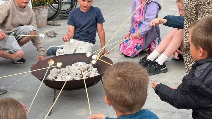 Børn spiser marshmallows med stokke.