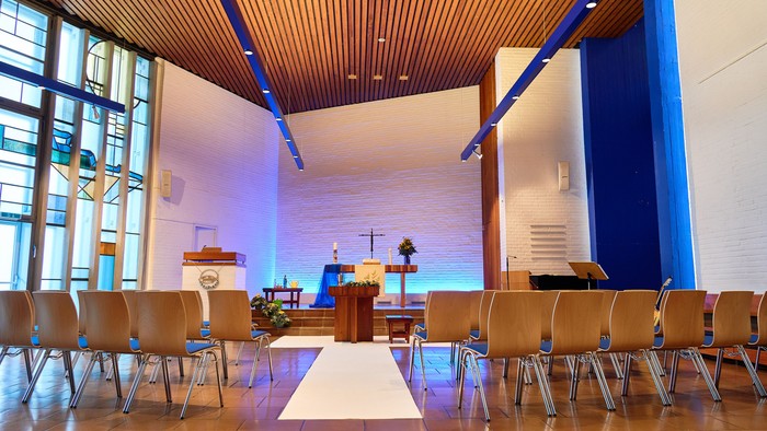 Moderne Kirche mit Holzstühlen und blauer Beleuchtung