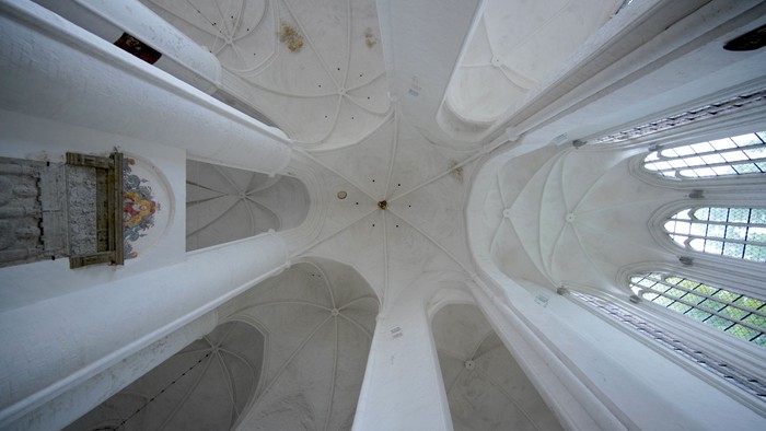 Gotische Kathedraleninnenräume mit hoch aufragenden weißen Rippengewölben und Buntglasfenstern.