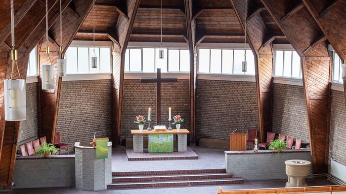 Ein moderner Wohnraum mit hohen Decken und großen Fenstern, eingerichtet mit Holz und grünen Akzenten.