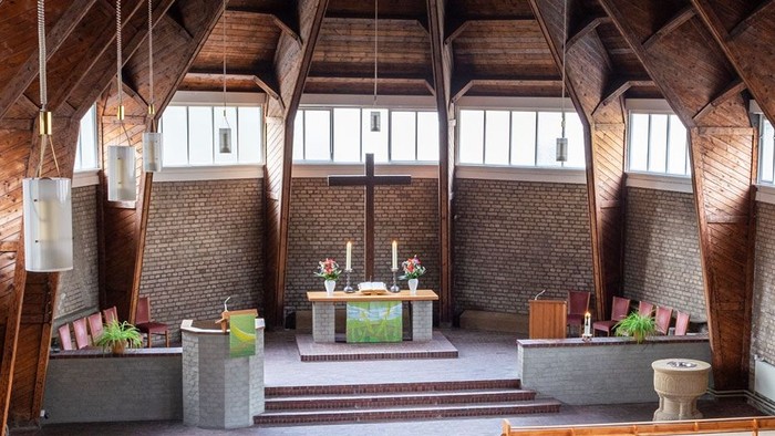 Ein moderner Wohnraum mit hohen Decken und großen Fenstern, eingerichtet mit Holz und grünen Akzenten.