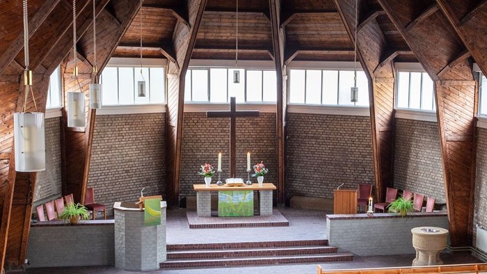 Ein moderner Wohnraum mit hohen Decken und großen Fenstern, eingerichtet mit Holz und grünen Akzenten.