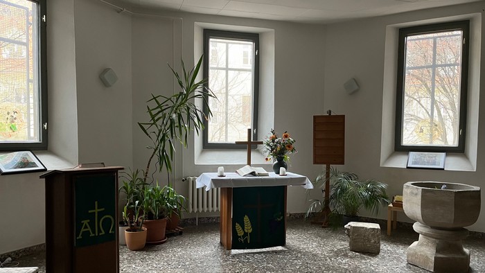 Kleine Kirche mit Altar, Topfpflanzen und zwei Fenstern