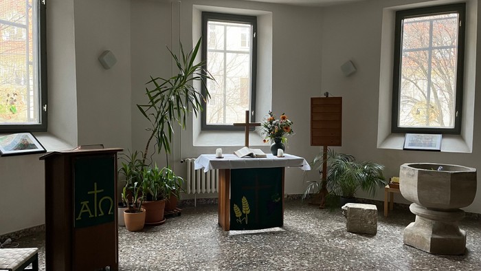 Kleine Kirche mit Altar, Topfpflanzen und zwei Fenstern