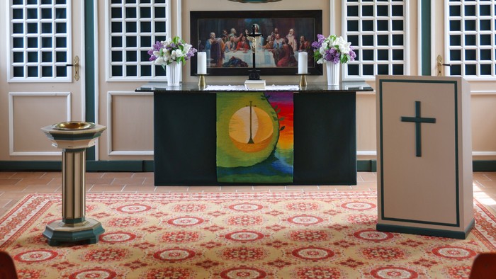 Elegante Kircheninnenausstattung mit verziertem Altar, Orgel und religiösen Symbolen an den Wänden.