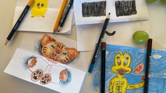 Farverige børnetegninger med farveblyanter, blyanter og skitser af en and, en kat og abstrakte former på papir.
