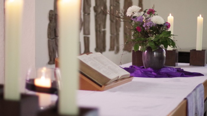 Tisch mit Kerzen, Buch und Blumen in einer Vase