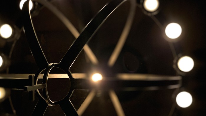 Moderne lysekrone med stjerneformet metalramme og klare, cirkulære pærer.