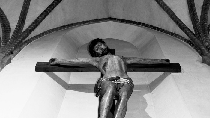 Eine Kreuzigungsstatue in einer Kirche mit gotischen Bögen.