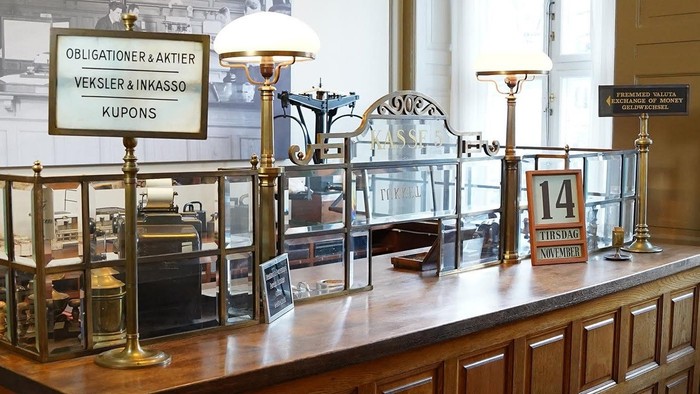 Gammelt træskranke med vintage kasseudstyr og oplyste skilte til transaktioner og rabatter.