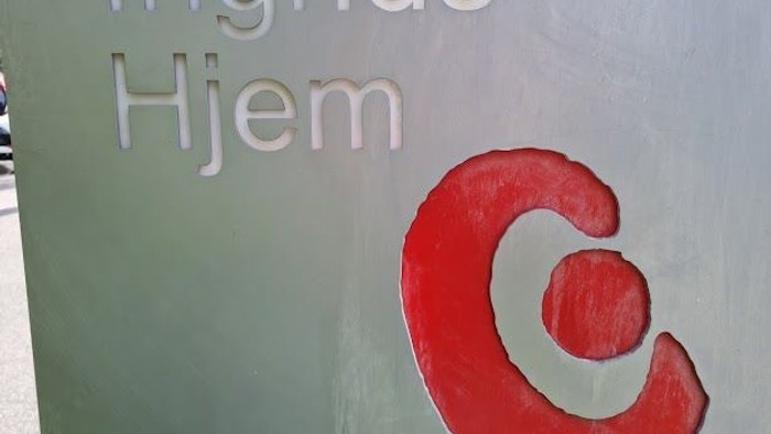 Grønne væg med hvidt skilt og rød bogstaver 