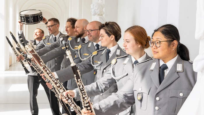 Plakat für ein Benefizkonzert des Kammerorchesters des Kasseler Militärmusikcorps mit uniformierten Musikern.