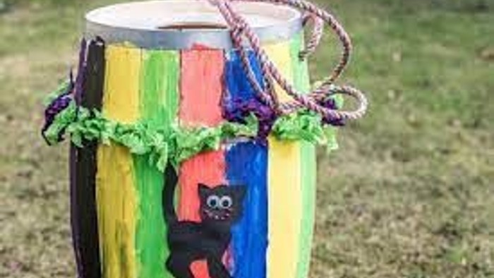 En farverig tromme med bælte og en lille figur på en græsplæne.