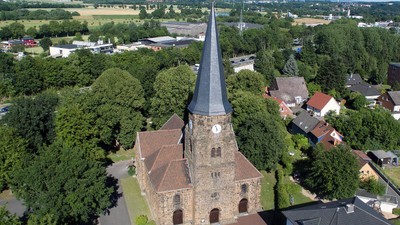 Luftaufnahme einer historischen Kirche, umgeben von üppigem Grün und einem malerischen Dorf.