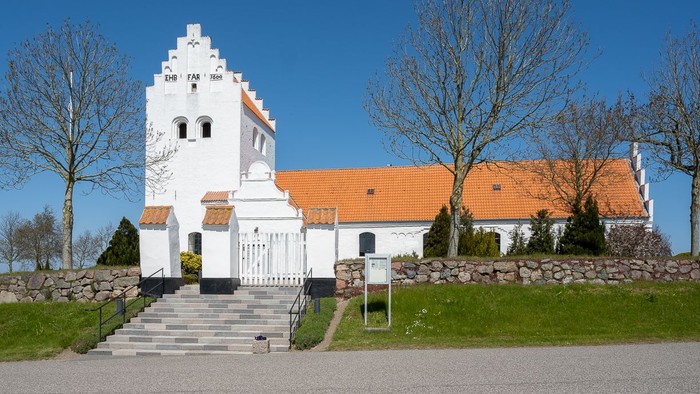 En lille, hvid kirke med orange tagtag og en smal trap til indgangen.